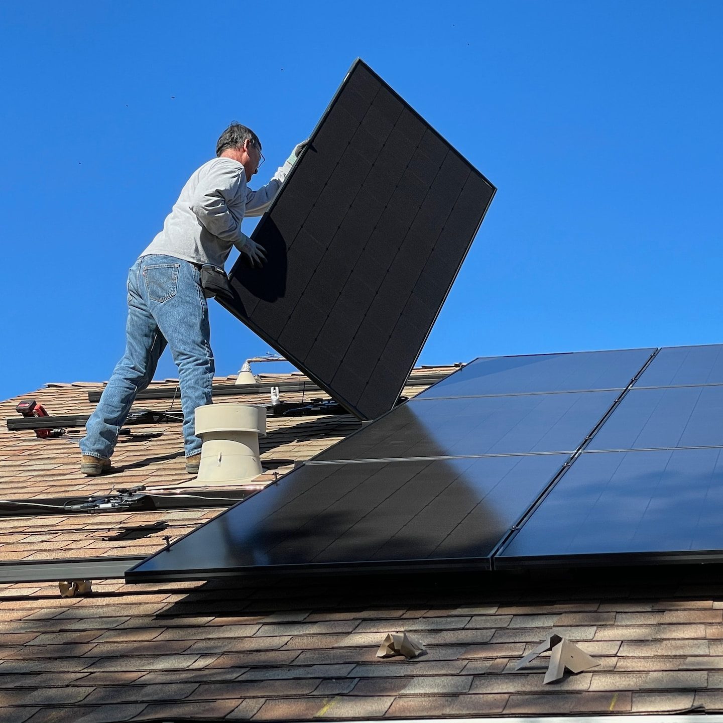 man in white dress shirt and blue denim jeans sitting on white and black solar panel